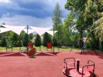 Trzy białe żagle wodoszczelne premium o wymiarach 4,2x4,2x5,9 m chroniące plac zabaw przed słońcem i deszczem.