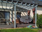 Wodoszczelny żagiel ogrodowy premium 2x2m w kolorze beżowym, zamontowany pod konstrukcją pergoli nad tarasem z hamakiem.