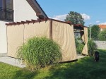 Brązowa pergola tarasowa z zamontowaną poziomą roletą rzymską premium Decor 4x4 w kolorze beżowym.