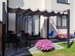 Roleta rzymska pozioma premium Decor 4x4 osłaniająca taras z meblami ogrodowymi i dziecięcymi huśtawkami.