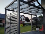 Biały pas altanowy przeciwsłoneczny 1x5 m przeplatany przez belki szarej, drewnianej pergoli tarasowej.