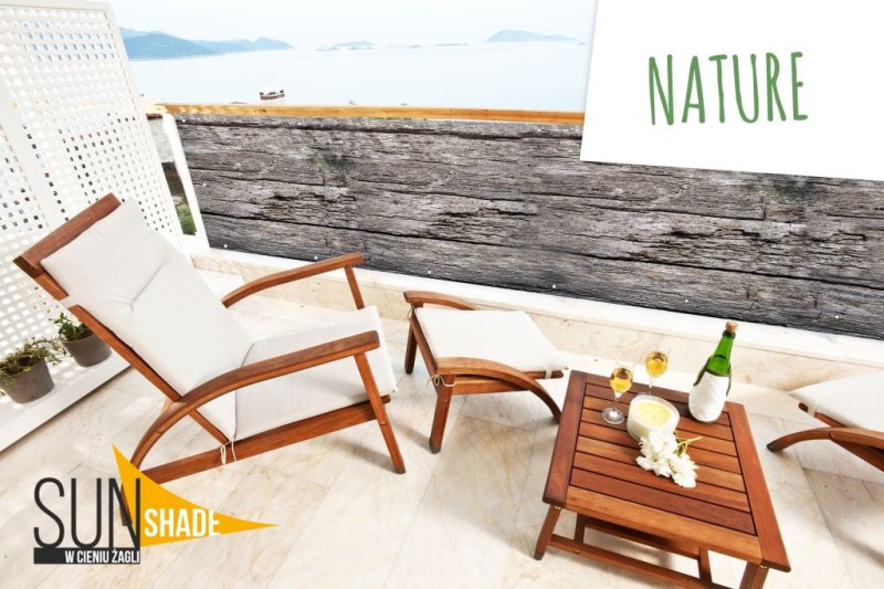 Graficzna osłona balkonowa z motywem starego drewna zamontowana na balustradzie tarasu z meblami ogrodowymi.