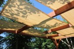 Beżowy pas altanowy przeciwsłoneczny HDPE 0,4x5m zamontowany na drewnianej pergoli w słonecznym ogrodzie.