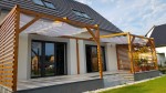 Biały żagiel wodoszczelny rozsuwany premium 2,04x2,48m zamontowany na drewnianej pergoli tarasowej.