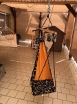 Beżowa kurtyna zewnętrzna o wymiarach 2,49x1,97 m osłaniająca taras z wiszącym fotelem i domkiem dla dzieci.