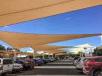 Piaskowe żagle przeciwsłoneczne HDPE chroniące samochody na parkingu przed słońcem w upalny dzień.