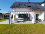 Wygodna strefa relaksu na tarasie z białą poziomą roletą rzymską premium Decor 4x4 o falistym kształcie.