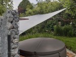 Szary kwadratowy żagiel ogrodowy wodoszczelny premium 3x3 zamontowany nad okrągłym jacuzzi w ogrodzie.