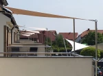 Beżowy żagiel wodoszczelny 1,05x2,43 m zamontowany na balkonie jako nowoczesna osłona przeciwsłoneczna.