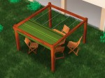 Brązowa drewniana pergola ogrodowa z meblami, którą osłania zielona pozioma roleta rzymska premium Decor 4x4.