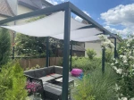 Wodoszczelny żagiel ogrodowy w kolorze popielatym o wymiarach 1,20x2,59 m zamontowany na metalowej pergoli.