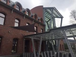 Brązowy trójkątny żagiel ogrodowy wodoszczelny zamontowany na elewacji nowoczesnej restauracji z cegły.