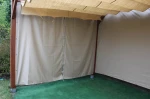 Szara zasłona tarasowa z nadrukiem jednostronnym o wymiarach 5,75x2,36 m, zamontowana w drewnianej altanie.