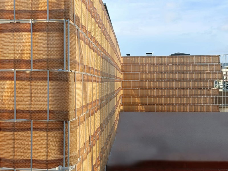 Beżowa osłona balkonowa z HDPE o gęstym splocie zamontowana na białej balustradzie tarasu.
