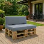 Sofa z palet z szarymi poduszkami ogrodowymi na tarasie, w tle ogród i zestaw mebli do siedzenia.