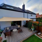 Beżowy żagiel przeciwsłoneczny HDPE czworobok na wymiar nad tarasem z meblami wypoczynkowymi.