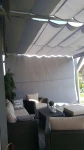 Zasłona boczna do pergoli z tkaniny meshflag o wymiarach 1,78x1,40 m w kolorze szarym na tarasowym zestawie wypoczynkowym.