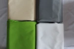 Cztery złożone tkaniny na zasłony lub flagi meshflag w kolorach beżowym, szarym, zielonym i białym.