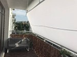 Biały wodoszczelny żagiel ogrodowy 3,95x3,79 m zamontowany jako osłona przeciwsłoneczna na balkonie z sofą.