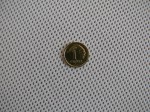 Mosiężna moneta 1 grosz leżąca na białym materiale pasów altanowych o strukturze drobnej siatki.