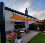 Pustynny żagiel przeciwsłoneczny HDPE 5x5 rozpięty nad nowoczesnym tarasem z meblami ogrodowymi i roślinami.