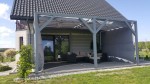 Szara kurtyna altanowa Premium zamontowana na bocznej i górnej części nowoczesnej, drewnianej konstrukcji tarasowej.