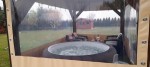 Przeźroczysta osłona tarasowa na wymiar osłaniająca altanę z jacuzzi i meblami ogrodowymi przed deszczem i wiatrem.