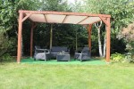 Brązowa drewniana pergola ogrodowa z meblami wypoczynkowymi i zamontowanym żaglowym dachem przeciwsłonecznym HDPE.