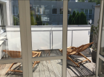 Biała osłona balkonowa na wymiar zamontowana na balustradzie tarasu z drewnianymi leżakami i podłogą.