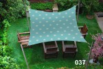 Wodoszczelny żagiel ogrodowy 3x4 m w kolorze morskim z motywem kół sterowych nad kompletem mebli drewnianych.