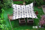 Wodoszczelny żagiel ogrodowy 3x4,5 m z graficznym wzorem kół, rozpięty nad drewnianymi meblami ogrodowymi na trawniku.