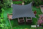 Wodoszczelny żagiel ogrodowy 3x4,5 m z graficznym wzorem, zawieszony nad drewnianymi meblami ogrodowymi na trawniku.