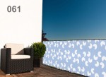 Niebieska osłona balkonowa z białym wzorem rastrowym zamontowana na barierkach tarasu z meblem ogrodowym.